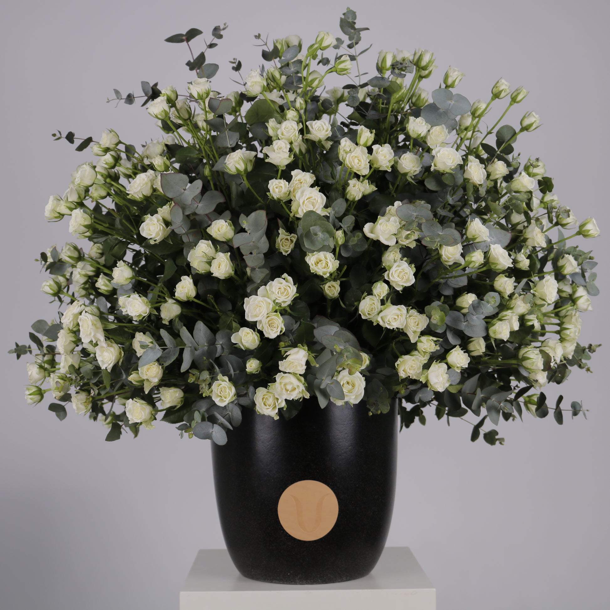 premium arrangement of white spray roses and eucalyptus in a stylish black vase.