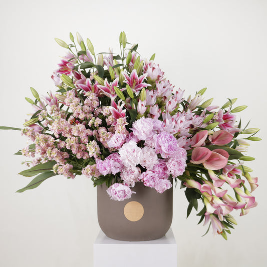 Luxury floral arrangement featuring pink lilies, peonies, and stocks in an elegant vase.