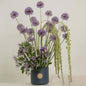 Elegant floral arrangement featuring Allium, clematis, and Amaranthus in a stylish blue vase.