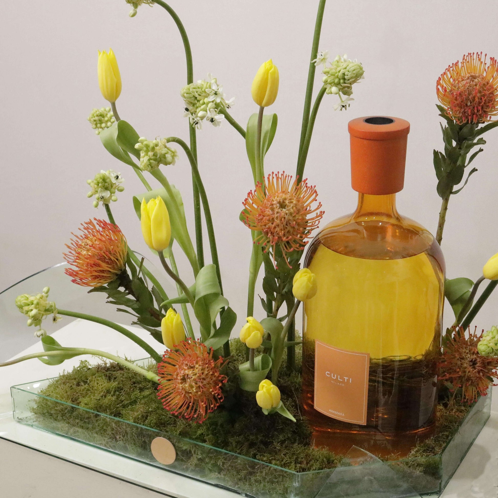 Exquisite Color Gift Aramara arrangement with Tulips Pins, Ornithogalum, and custom leaf tray, featuring a luxurious bottle centerpiece.