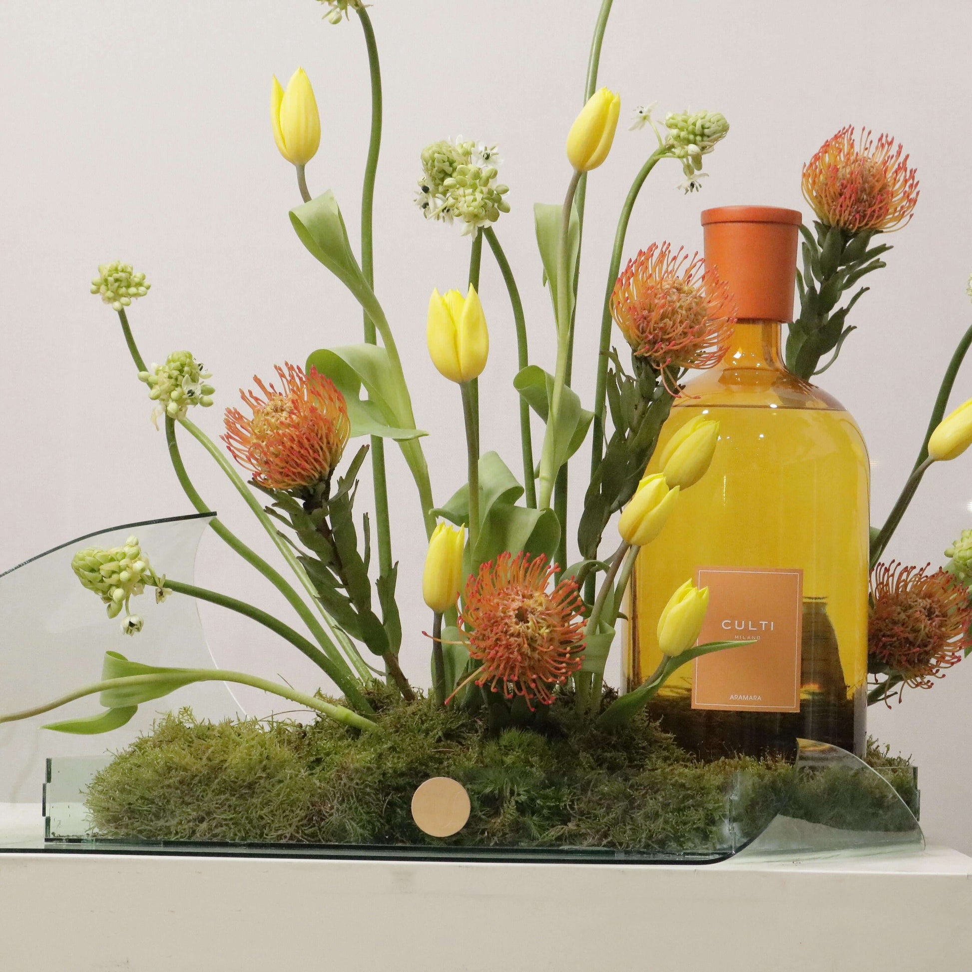 Luxurious floral arrangement with Tulips Pins, Ornithogalum, glass tray, and decorative bottle. Exquisite gift for elegance and beauty.