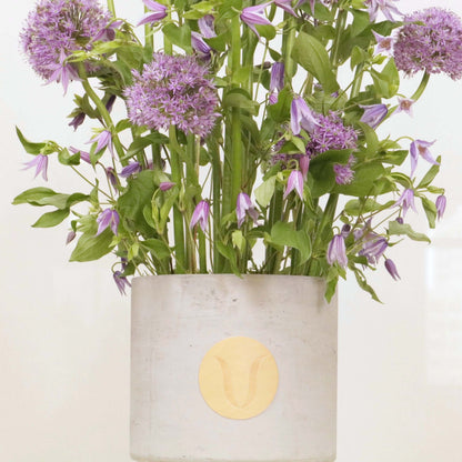 Elegant floral arrangement with tall Alliums and Clematis in a modern vase.