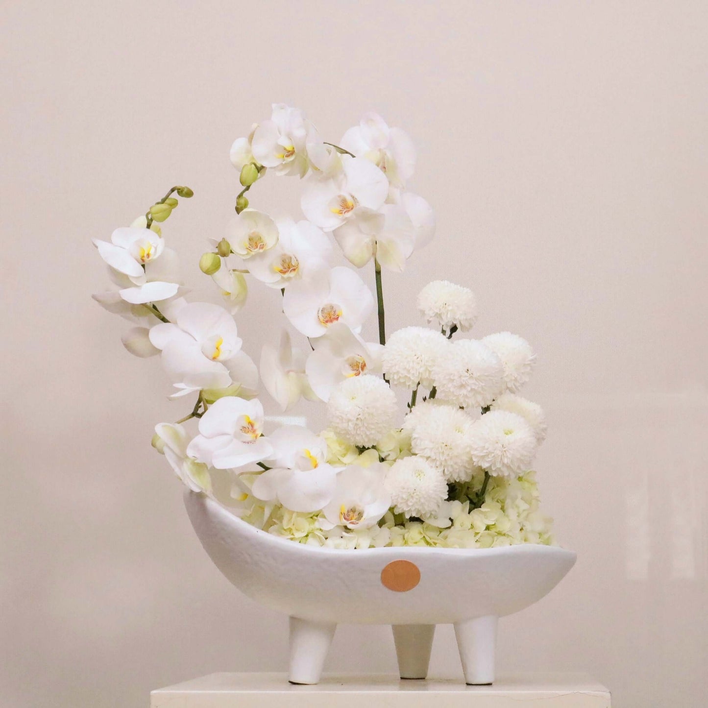Luxurious Sonus Albus floral arrangement with white Phalaenopsis orchids, hydrangeas, and ping-pong blooms in an elegant bowl.