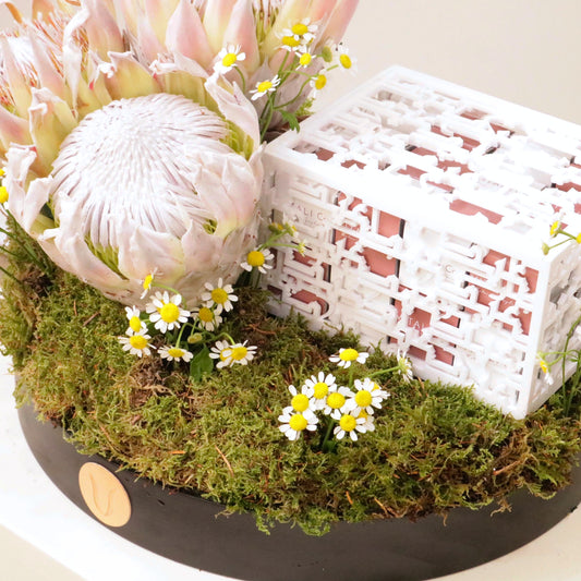 Luxurious Coco Delights Eid gift tray with Swiss chocolate, King Protea, and Matricaria flowers in a festive arrangement.