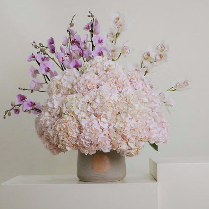 Floral arrangement with pink hydrangeas, pink orchids, and purple cymbidium; inspired by Italian song 'Caruso' for elegance.